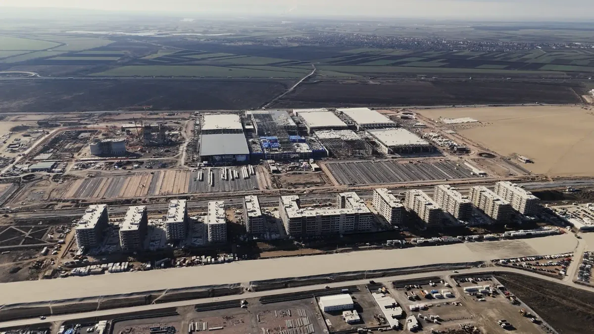 Aerial photo of the Expo 2027 construction site in Surčin in January 2026: half-built exhibition halls, rows of new apartment blocks and a wide road corridor in the foreground, with flat farmland beyond