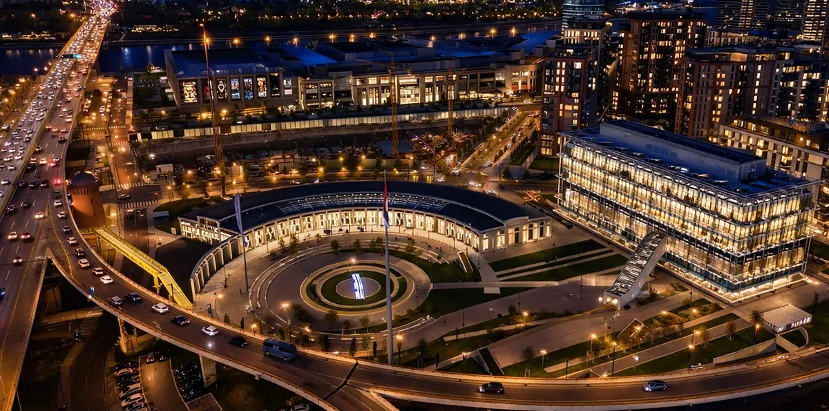 Ložionica complex in Belgrade lit up at night, seen from above, with the round atrium, the river-side buildings and the roads around it