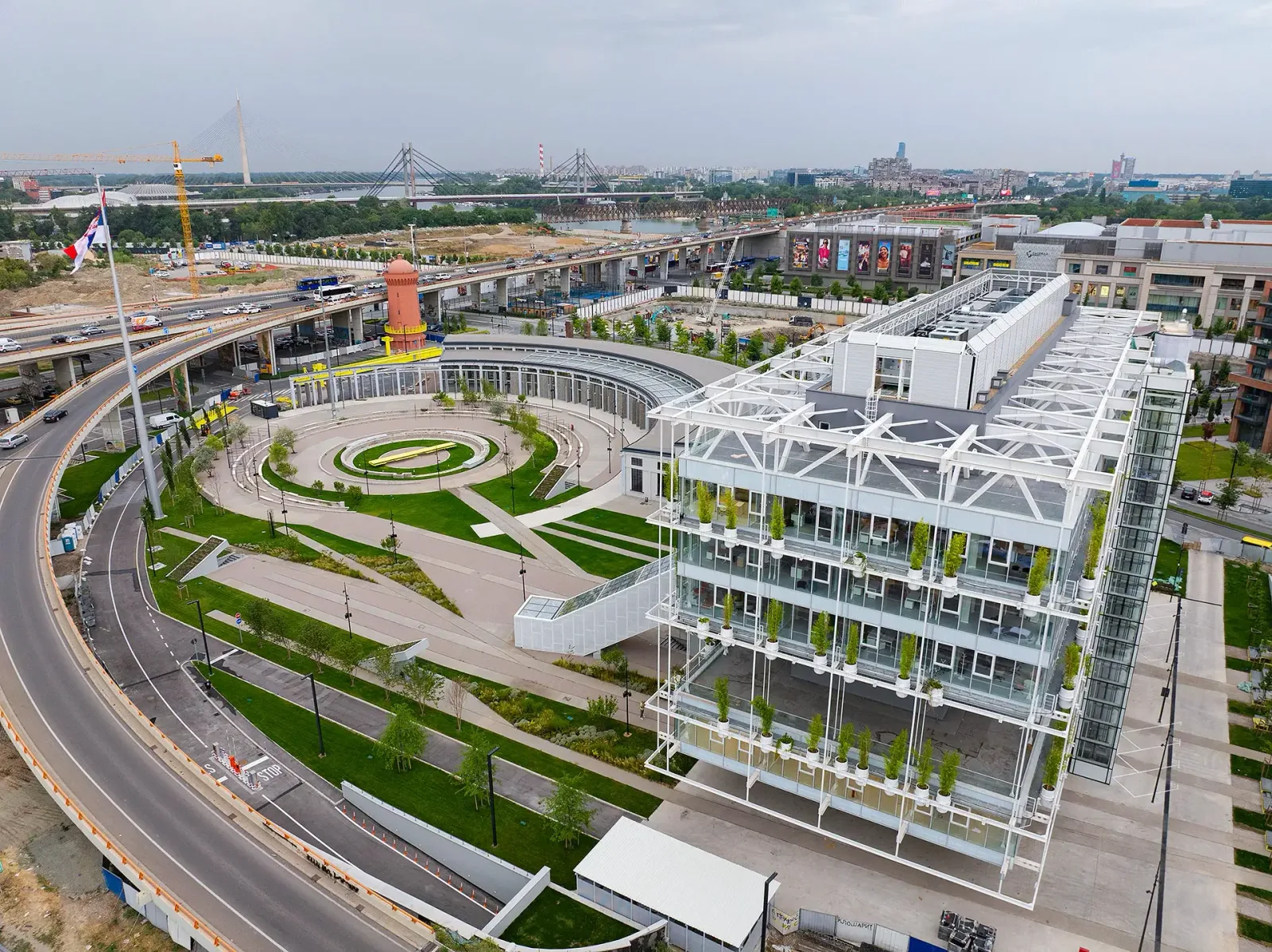 Aerial view of Ložionica in Belgrade: the round open-air atrium inside the old railway roundhouse, next to a glass building with green façades