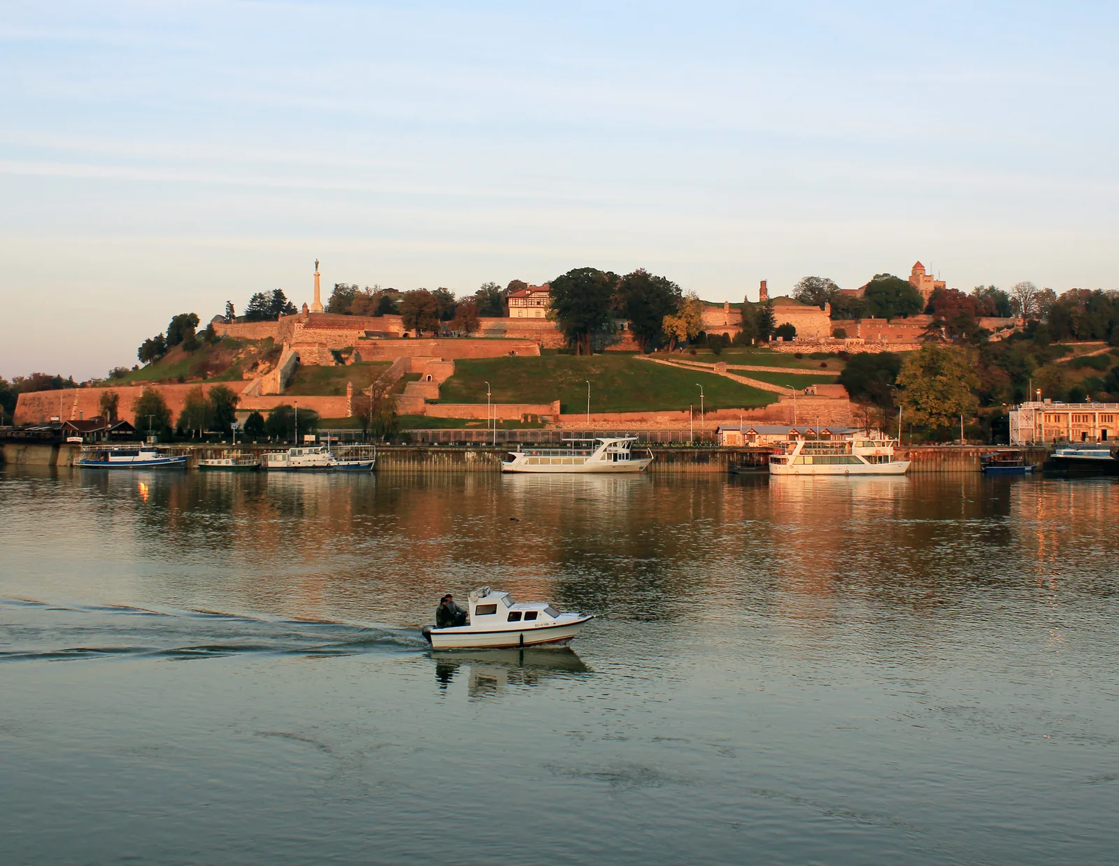 De vesting van Belgrado op de Kalemegdan-heuvel in warm avondlicht boven de Sava, met boten aan de kade