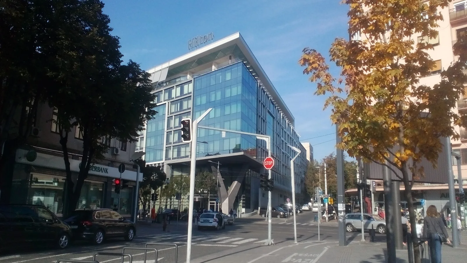 Glazen gevel van Hilton Belgrade aan de Kralja Milana, met herfstbomen ervoor