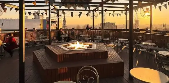 Rooftop deck in Belgrade at sunset with a square fire pit in the centre and small groups seated around the terrace