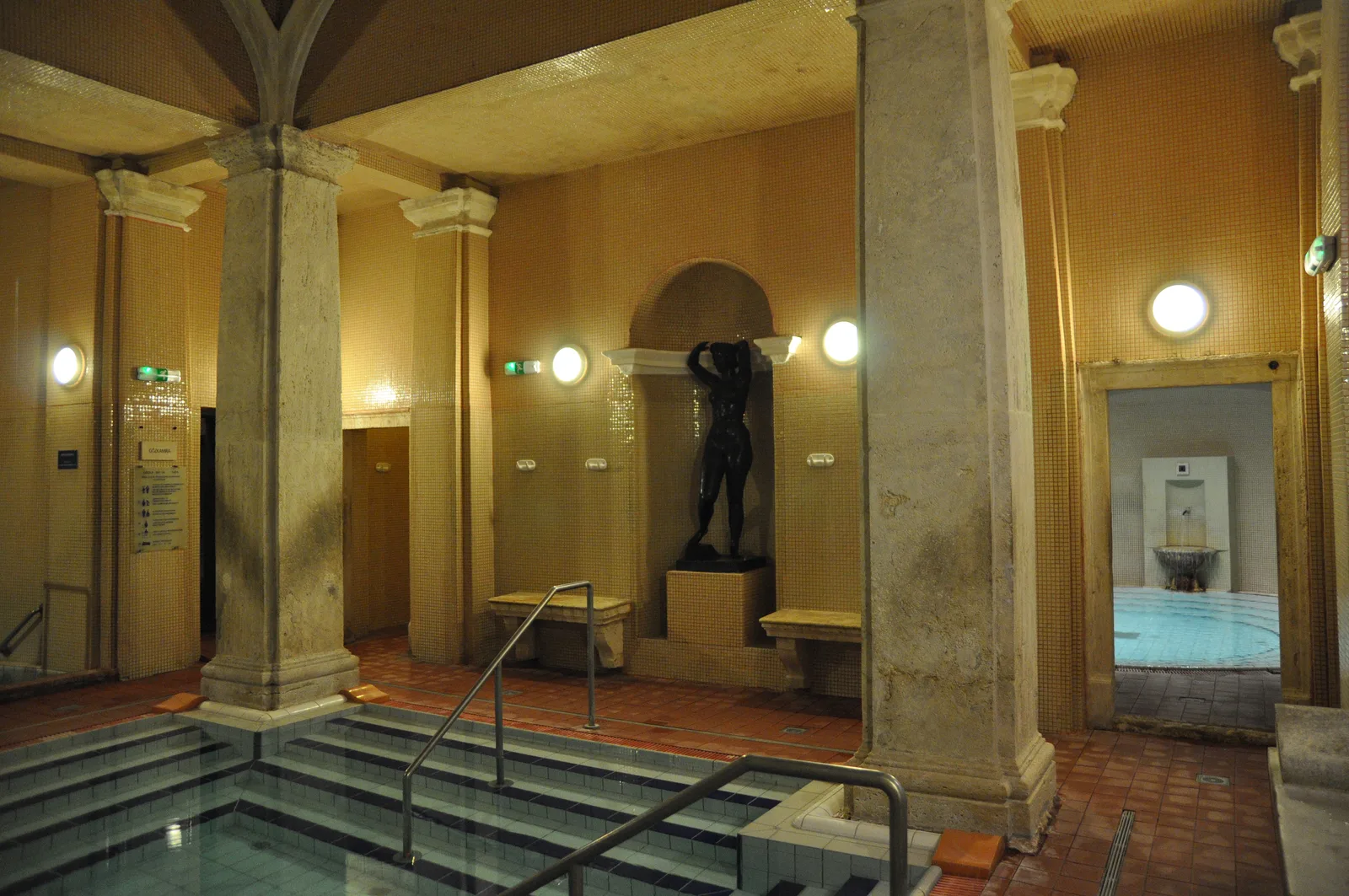 Bassin thermal intérieur des thermes Lukács à Budapest, entouré de colonnes et éclairé par des lampes murales
