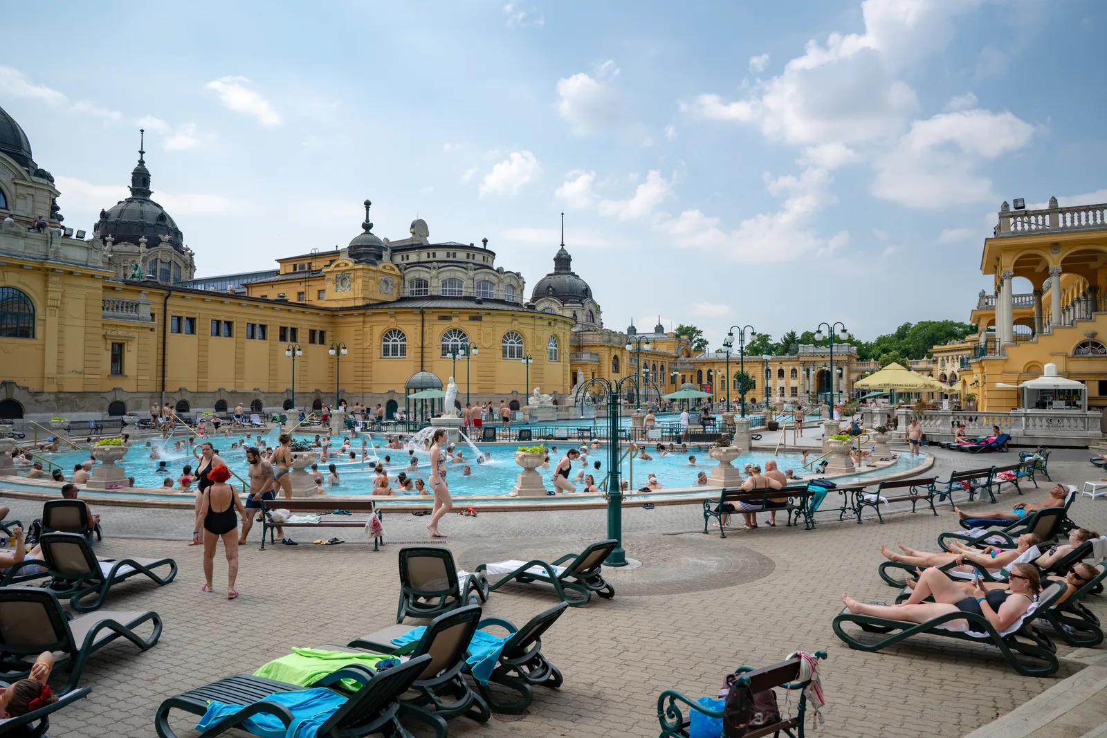 Baigneurs dans les bassins extérieurs des thermes Széchenyi en journée, transats au premier plan et dômes du bâtiment au fond